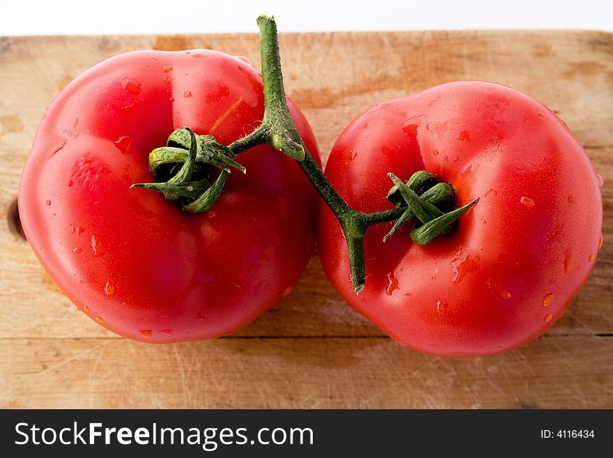 Tomatoes colorful, with water drops, on wooden board, studio shot. Tomatoes colorful, with water drops, on wooden board, studio shot