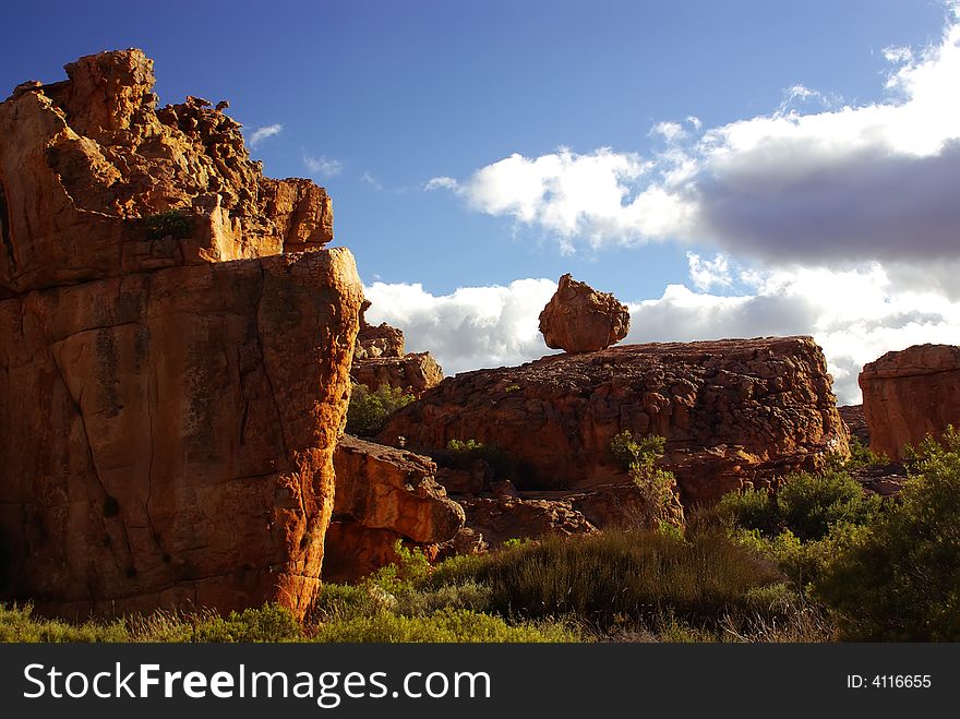 Yellow red stones and cliffs on red soil. Yellow sand and green bushes, deep blue cloudy sky. mountains of South Africa. Yellow red stones and cliffs on red soil. Yellow sand and green bushes, deep blue cloudy sky. mountains of South Africa