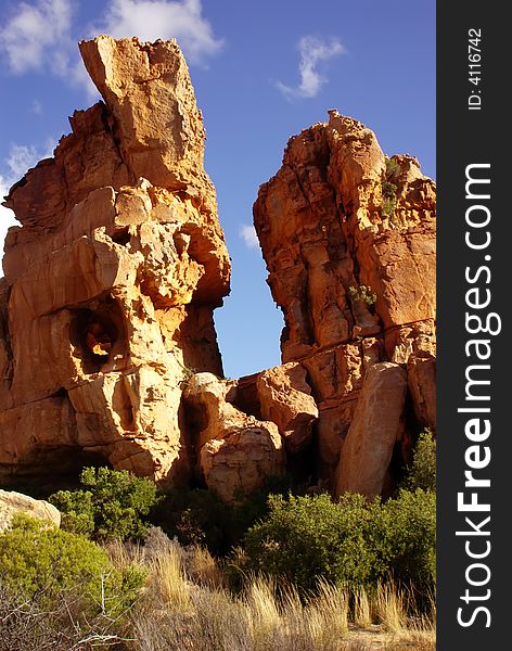 Yellow red stones and cliffs on red soil. Yellow sand and green bushes, deep blue cloudy sky. mountains of South Africa. Yellow red stones and cliffs on red soil. Yellow sand and green bushes, deep blue cloudy sky. mountains of South Africa