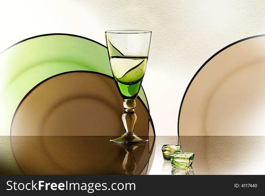 A glass beside a stack of white plates - on white background. A glass beside a stack of white plates - on white background