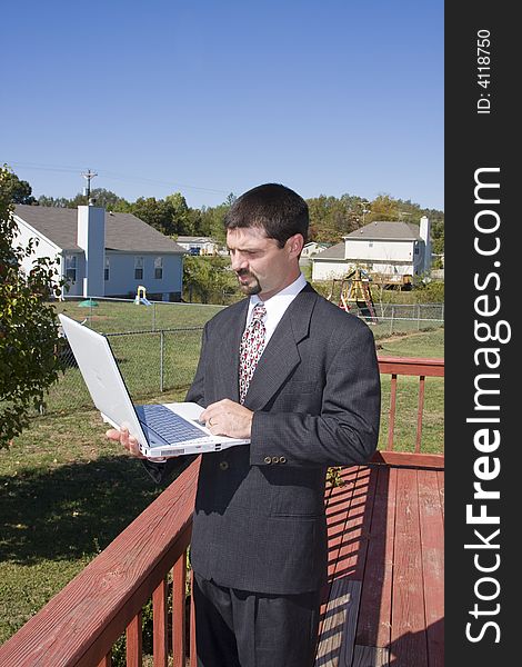 Young executive working at home through the internet ,standing on deck and communicating with his office computer. Young executive working at home through the internet ,standing on deck and communicating with his office computer