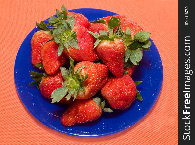 Still-life with fresh strawberry on the blue dish and orange background. Still-life with fresh strawberry on the blue dish and orange background