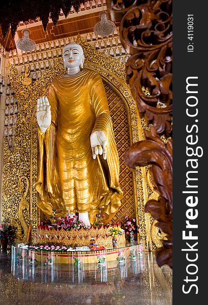 Standing golden buddha statue with a wood carving at the front photo. Standing golden buddha statue with a wood carving at the front photo