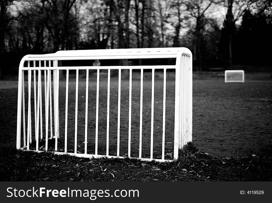 Two goal cages in black&white with a long autumn field between them. Two goal cages in black&white with a long autumn field between them