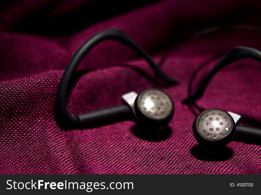 Pair of earphones on the red background macro details