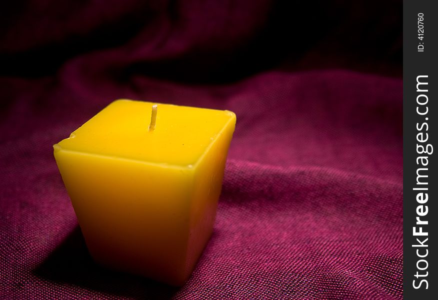 Single yellow candle without a light macro studio red background. Single yellow candle without a light macro studio red background