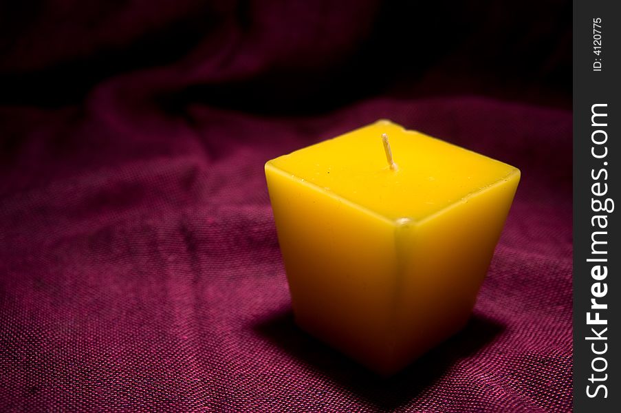 Single yellow candle without a light in red background macro. Single yellow candle without a light in red background macro