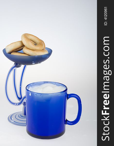 Milk in a blue cup and vase with bagels. Milk in a blue cup and vase with bagels.