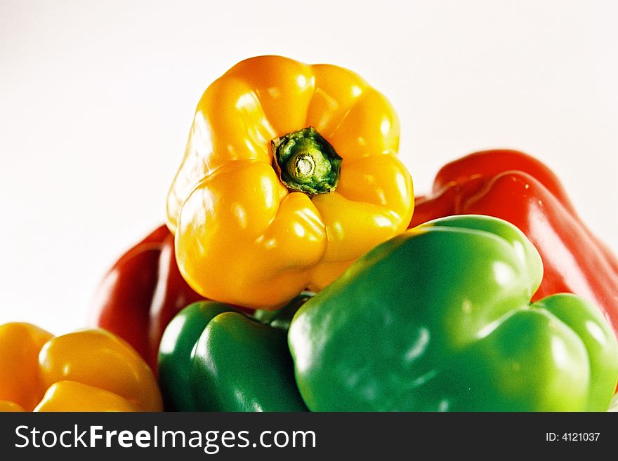 A close up view of a bowl of yellow, green and red capsicum.