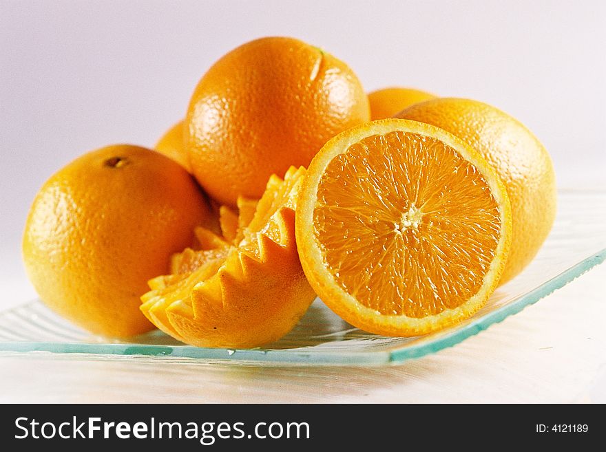 A plate of fresh oranges, whole and sliced