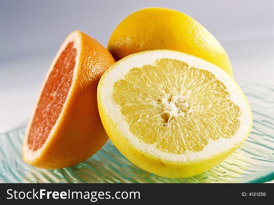 A close up view of a sliced lemon and grapefruit on a plate. A close up view of a sliced lemon and grapefruit on a plate