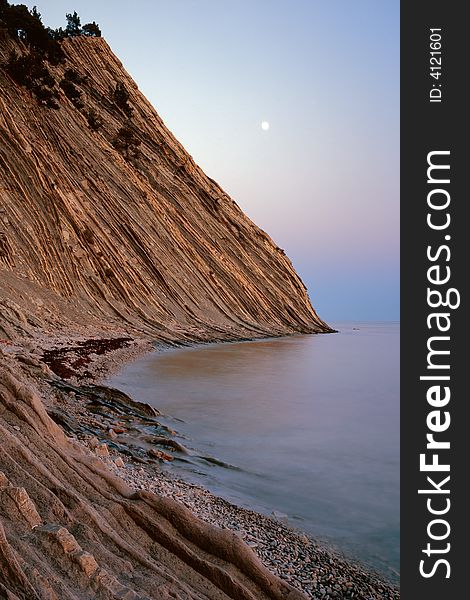 Evening landscape with rocks, sea and moon