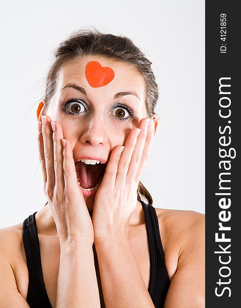 Attractive woman with red heartshaped plaster on forehead. Seems to be totally surprised. Attractive woman with red heartshaped plaster on forehead. Seems to be totally surprised