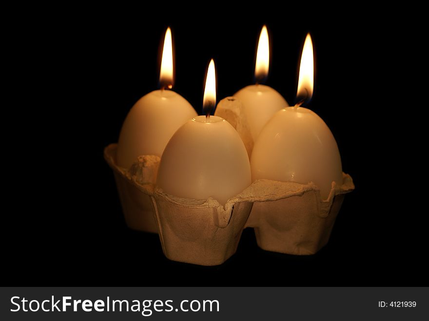 Four candles-eggs in box on the black background