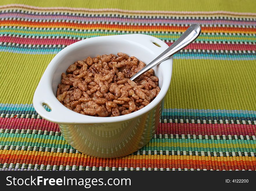 Cereal in a green bowl on a colorful placemat. Cereal in a green bowl on a colorful placemat