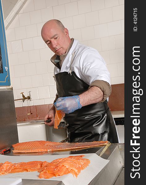 Fishmonger cutting slices of smoked salmon fresh from the smoke house. Fishmonger cutting slices of smoked salmon fresh from the smoke house