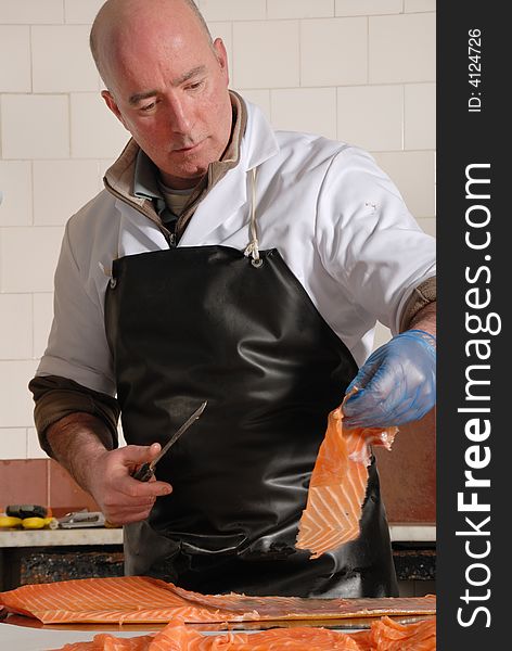 Fishmonger cutting slices of smoked salmon fresh from the smoke house. Fishmonger cutting slices of smoked salmon fresh from the smoke house