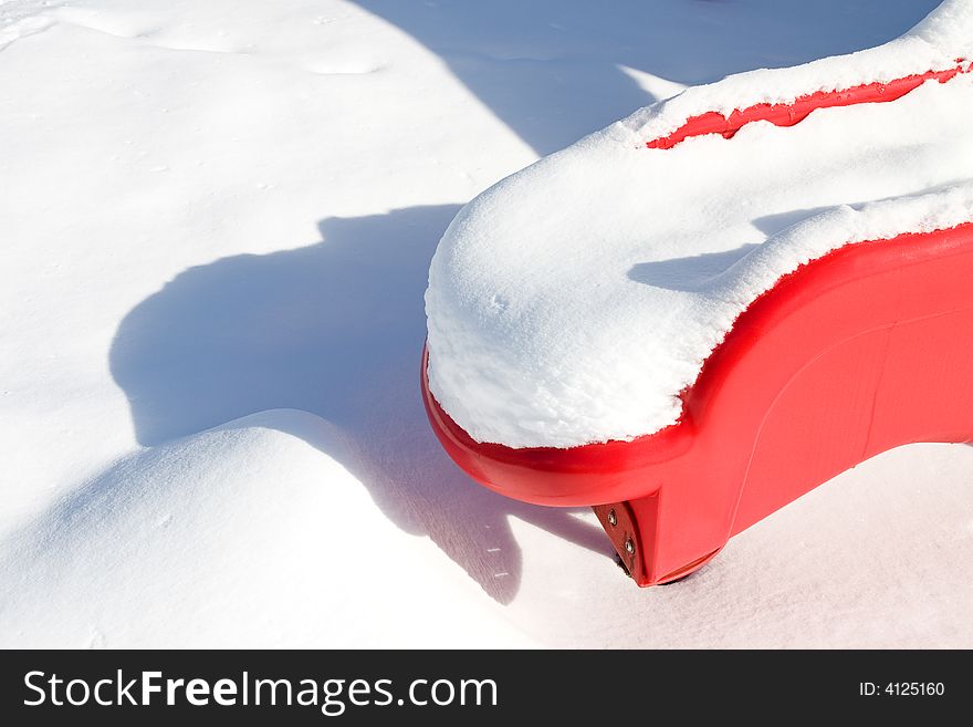 The bottom of a red playground slide in fresh fluffy snow. The bottom of a red playground slide in fresh fluffy snow