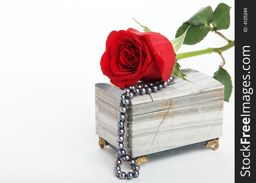 Beautiful red rose lying on box with black pearls