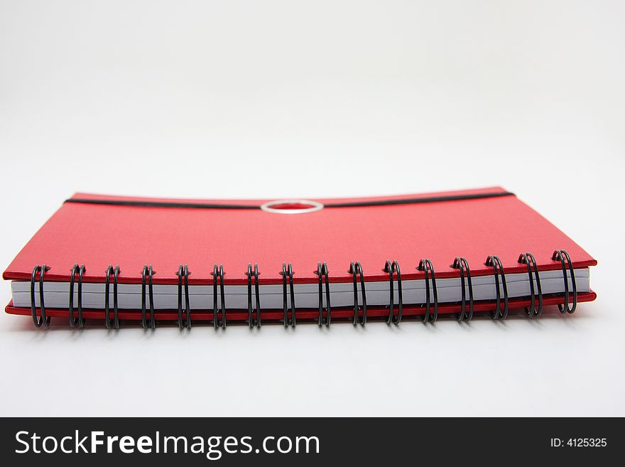Red notebook lying closed on white