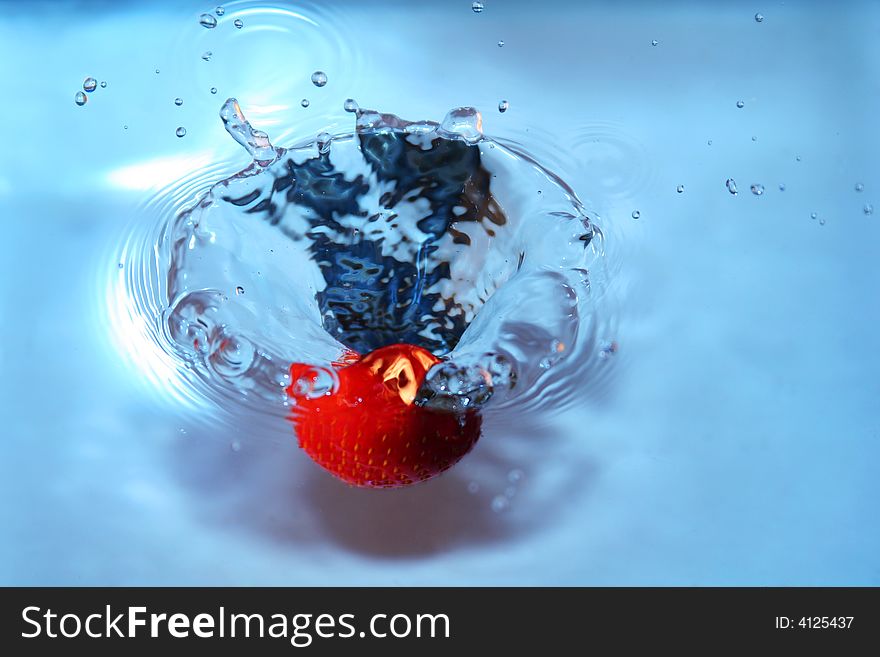 Strawberry falling into water, splashing water. freshness and purity implied. Strawberry falling into water, splashing water. freshness and purity implied
