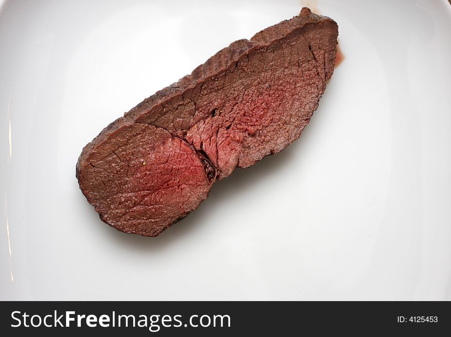Slice of medium raw beef on a plate, isolated. Slice of medium raw beef on a plate, isolated