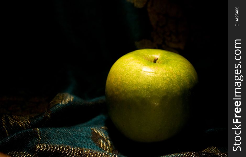 Single greeen apple on the textile background macro