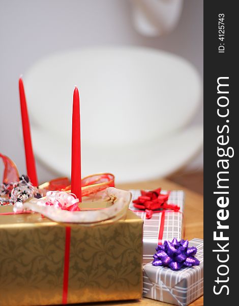 Christmas present on a table, ribbons and candle decorations around. Christmas present on a table, ribbons and candle decorations around