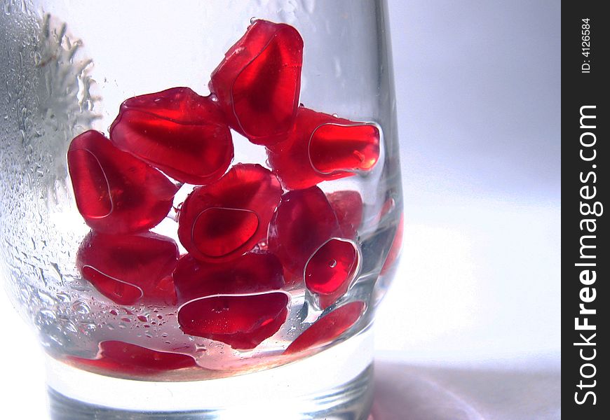 Grains of a pomegranate similar to precious rubies in a transparent glass. Grains of a pomegranate similar to precious rubies in a transparent glass