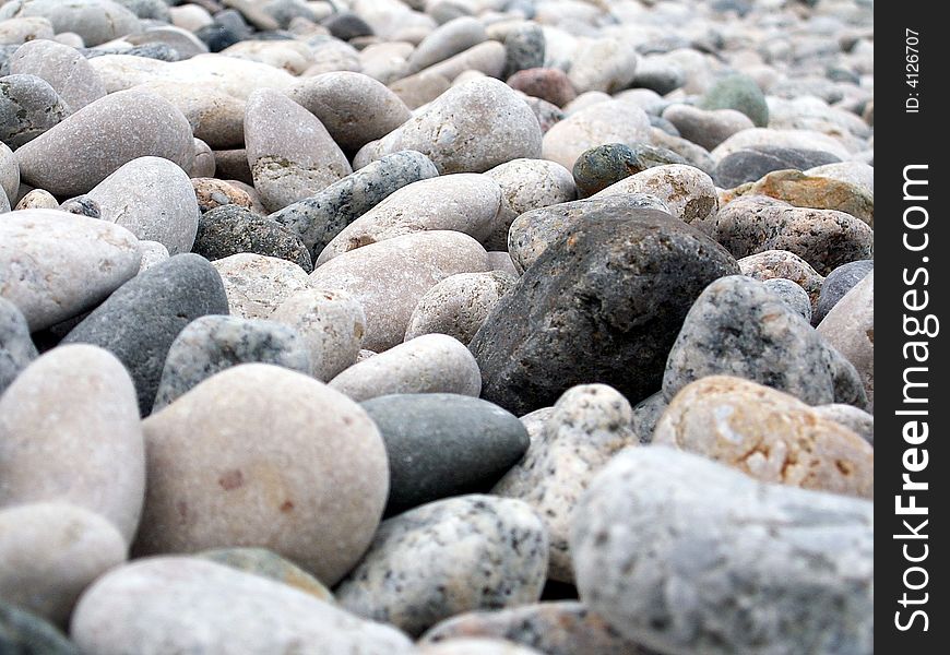 Gravel-stones on the beach shore. Most of pebble rocks has light-gray color with one black in the center. Gravel-stones on the beach shore. Most of pebble rocks has light-gray color with one black in the center.