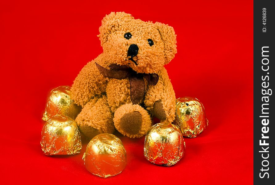 Teddy bear with sweetis on red background