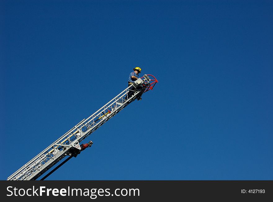 Firefighter at the top of a ladder truck's ladder. Firefighter at the top of a ladder truck's ladder