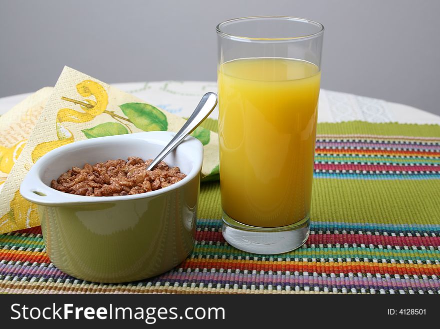 Cereal in a green bowl with orange juice. Cereal in a green bowl with orange juice