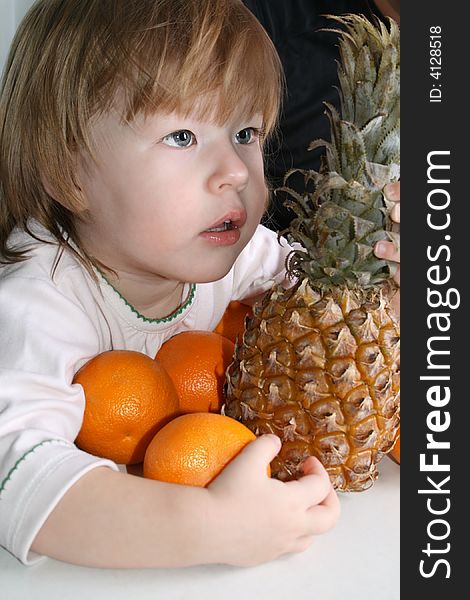 Girl holds in her hands oranges and pineapple. Girl holds in her hands oranges and pineapple