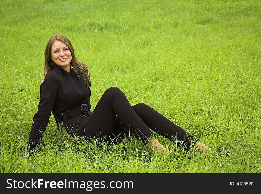 The beautiful girl sits on a green grass