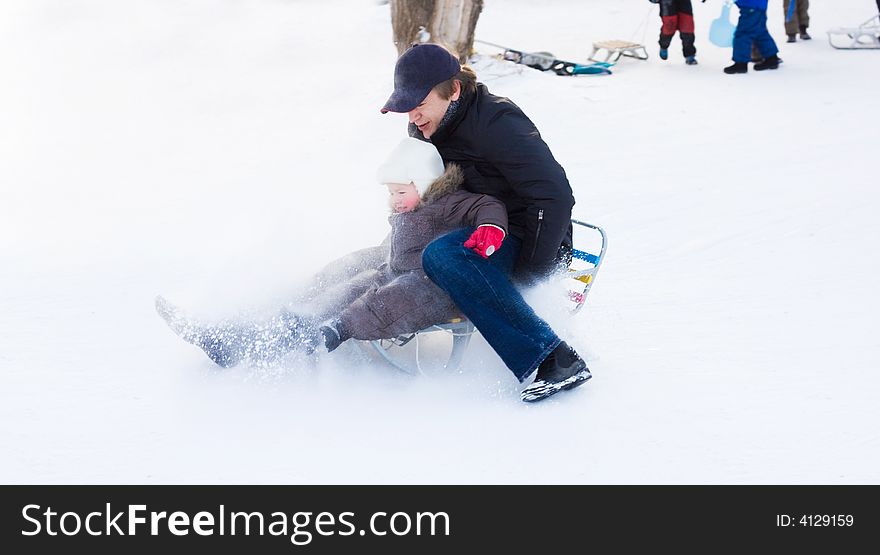 Winter recreation. Father and son having fun sliding downhill