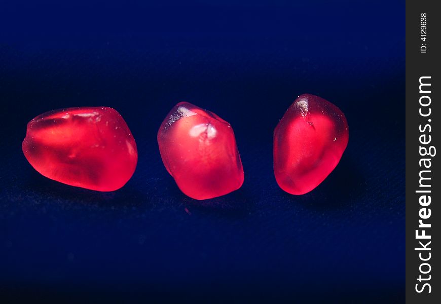 Three grains of a pomegranate on a dark background