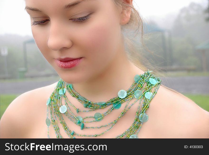 Beautiful Girl in fog wearing a green necklace. Beautiful Girl in fog wearing a green necklace