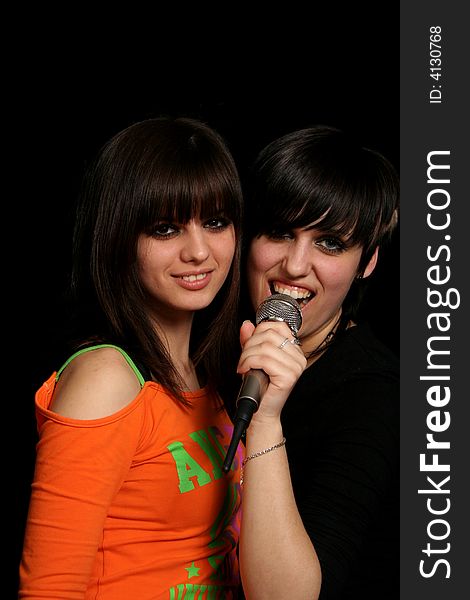 Two girls with a microphone, on black background