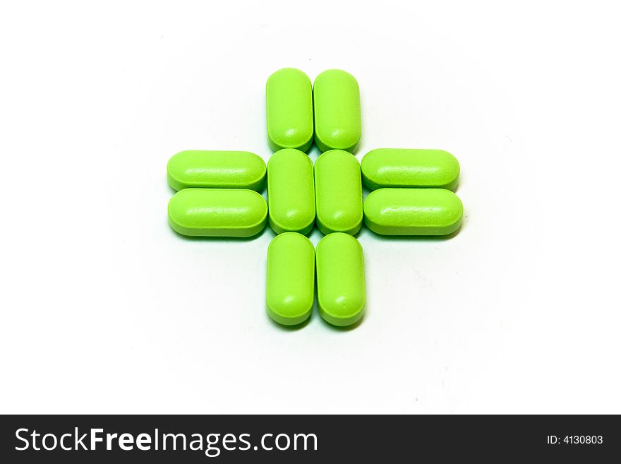 A green cross of pills on a white background