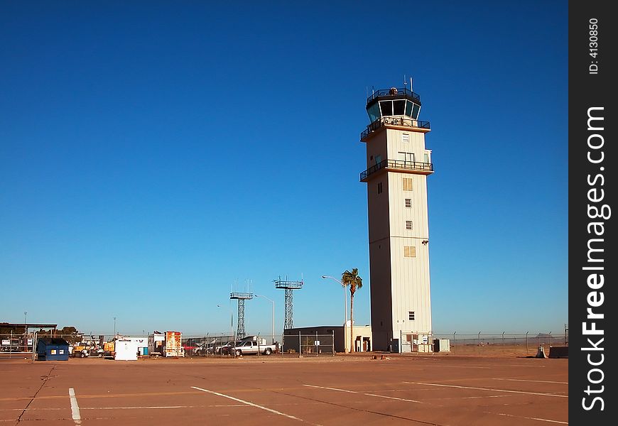 An airport control tower and tarmac shot against a stunning, clear blue sky. An airport control tower and tarmac shot against a stunning, clear blue sky