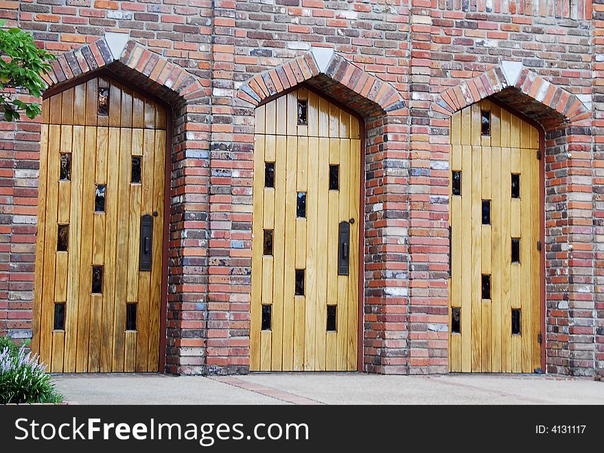 Three Wooden Doors surrounded by brick arches.