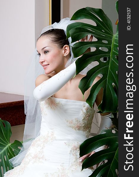 A happy bride near the big leaf of the flower