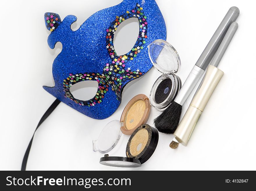 Blue carnival mask and gold eyeshadows with brush on white. Blue carnival mask and gold eyeshadows with brush on white