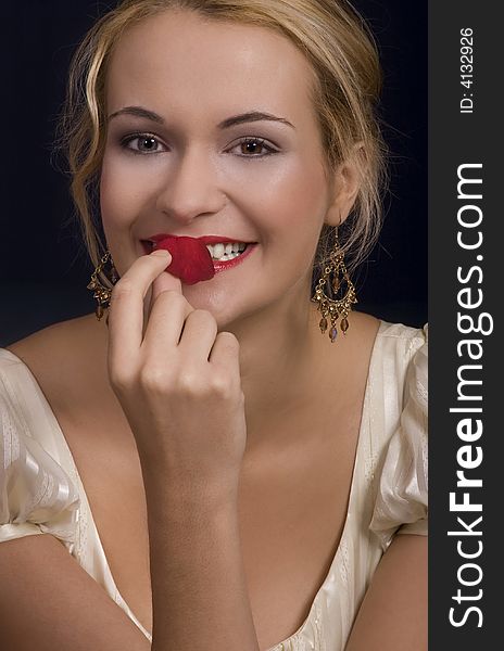 Beautiful blond girl kissing and smelling a rose petal wearing dress. Beautiful blond girl kissing and smelling a rose petal wearing dress