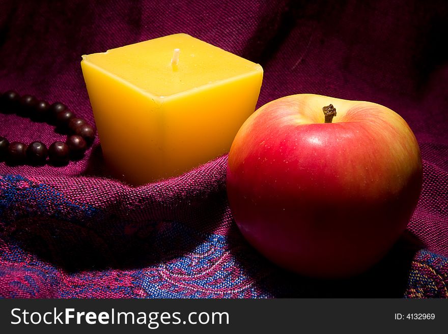 Red apple candle and wooden necklace macro studio. Red apple candle and wooden necklace macro studio