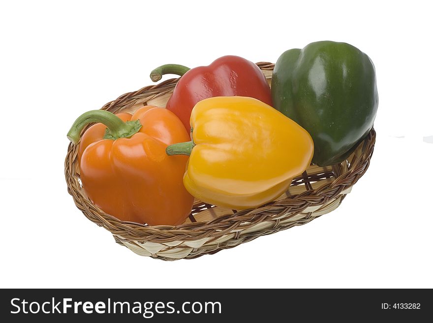 Red, green, yellow and orange pepper in the basket on the white backgrounds