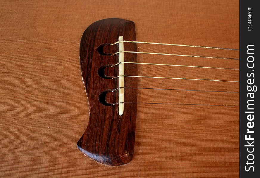 Brown acoustic bridge of a wooden guitar. Brown acoustic bridge of a wooden guitar