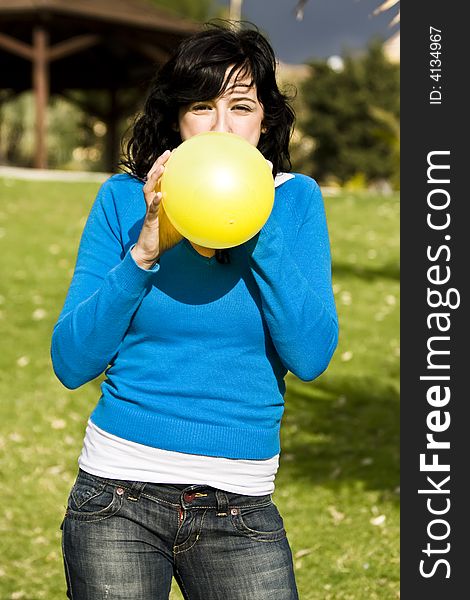 Teen inflating yellow balloon in the park