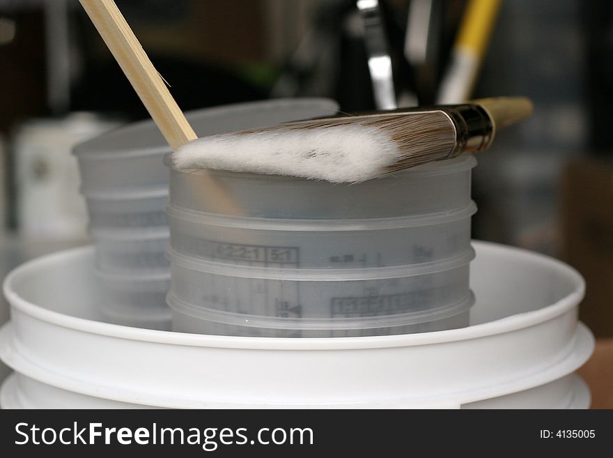 Paint brush with stir stick on bucket